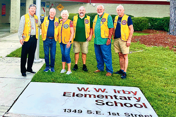 NOW — August 2025:  Members of the Alachua Lions Club assist with traffic control at W.W. Irby Elementary School on Aug. 11, 2025, the first day of the 2025-26 school year. This year marks the club’s 33rd consecutive year providing safety support for the school’s youngest students.